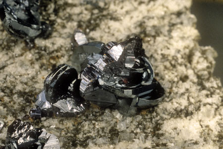 Knopfrutilvielling mit Hämatit| Auf einem zentralen Knopfrutilvielling (Kantenlänge 12 mm) sind Hämatittafeln orientiert aufgewachsen, auf die wiederum prismatische Rutile orientiert aufgewachsen sind 